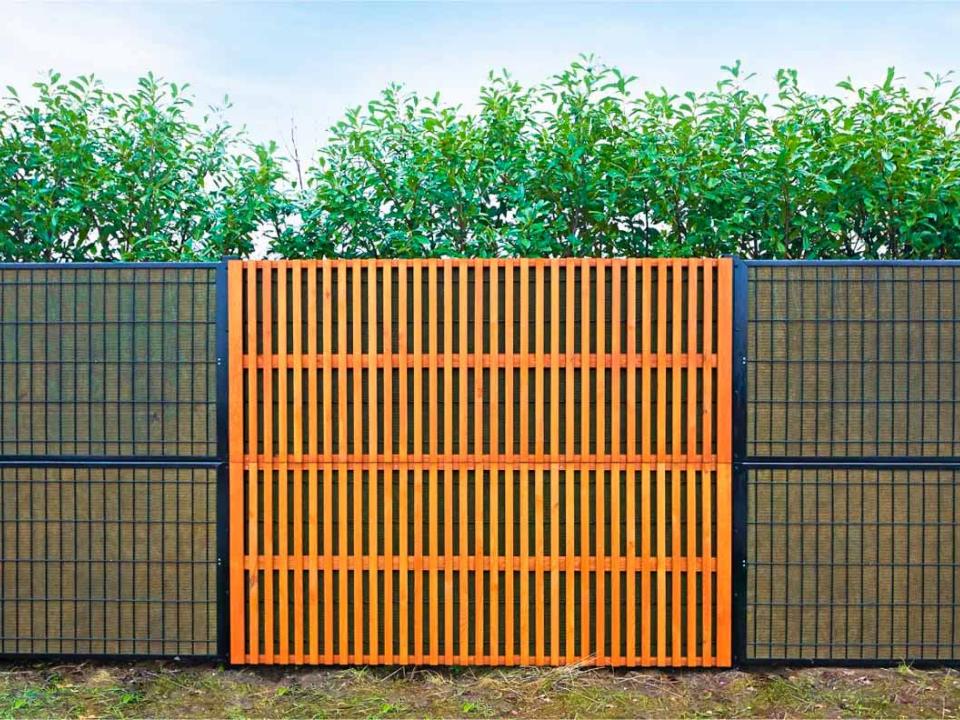 Grønt støjhegn med dør ved lejlighedskompleks